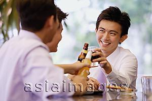Asia Images Group - Young men at bar counter toasting with drinks