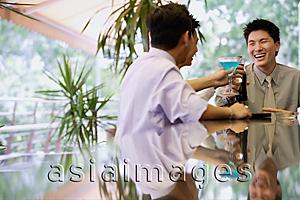 Asia Images Group - Young men at bar counter, raising drinks for a toast
