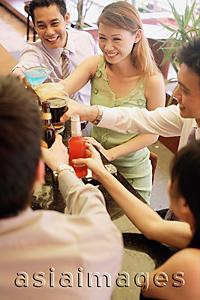 Asia Images Group - Friends at bar counter raising drinks for a toast, high angle view