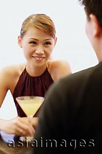 Asia Images Group - Young woman with cocktail glass, man facing her