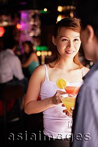Asia Images Group - Couple standing, holding drinks, over the shoulder view