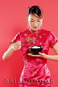 Asia Images Group - Woman in Cheongsam, holding bowl of rice and chopsticks, looking down