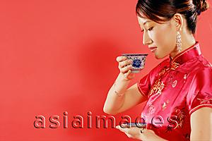 Asia Images Group - Woman holding teacup, looking down, sideview