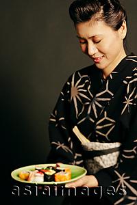 Asia Images Group - Woman in Japanese costume, holding plate of Japanese food