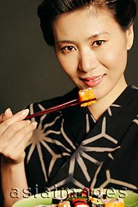 Asia Images Group - Woman in Japanese costume, eating sushi, portrait