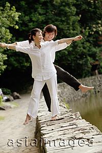 Asia Images Group - Couple balancing along ledge, arms outstretched