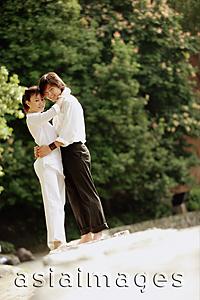 Asia Images Group - Couple standing in park, hugging, looking at camera