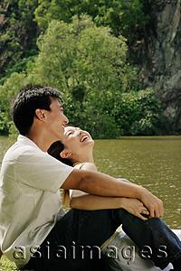 Asia Images Group - Couple sitting by lake, laughing