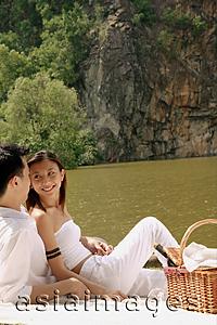 Asia Images Group - Couple sitting by a lake, with picnic basket