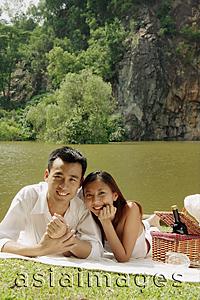 Asia Images Group - Couple by a lake, with picnic basket, looking at camera
