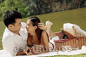 Asia Images Group - Couple by a lake, with picnic basket, looking at each other