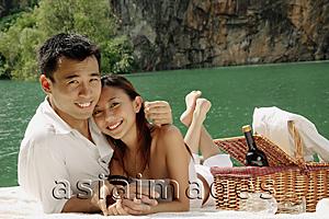 Asia Images Group - Couple having picnic by a lake, looking at camera