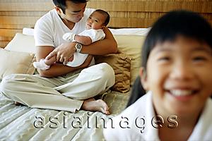 Asia Images Group - Father holding baby, older child in foreground