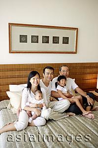 Asia Images Group - Three generation family on bed, looking at camera