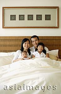 Asia Images Group - Father and mother with two children in bed, portrait