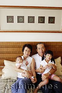Asia Images Group - Grandparents with grandchildren, sitting on bed, looking at camera