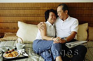 Asia Images Group - Older couple lying on bed, hugging