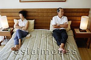 Asia Images Group - Older couple lying apart on bed, arms crossed
