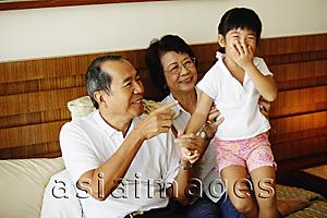 Asia Images Group - Grandparents with granddaughter, granddaughter covering mouth with hand