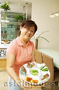 Asia Images Group - Woman holding tray of cakes, looking at camera