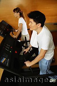 Asia Images Group - Couple in gym using treadmill