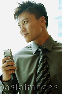 Asia Images Group - Businessman holding mobile phone, looking away