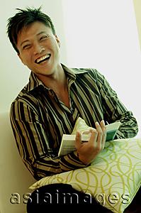 Asia Images Group - Man holding a book, looking at camera, smiling