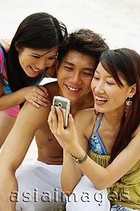 Asia Images Group - Young adults looking at mobile phone
