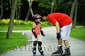 Asia Images Group - Father and daughter wearing inline skates, standing face to face