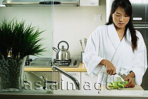 Asia Images Group - Woman in kitchen, cutting cucumber