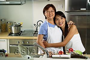 Asia Images Group - Mother with adult daughter in kitchen, looking at camera