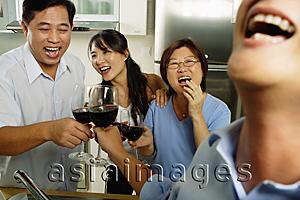 Asia Images Group - Two men and two women, in kitchen, toasting with wine glasses, laughing