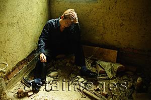 Asia Images Group - Man sitting in empty room, hand on head