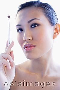 Asia Images Group - Woman looking at camera, holding make-up brush