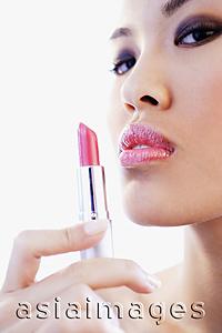 Asia Images Group - Woman holding lipstick, looking at camera