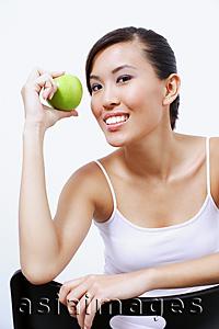 Asia Images Group - Woman holding apple, looking at camera