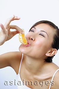 Asia Images Group - Woman eating orange slice