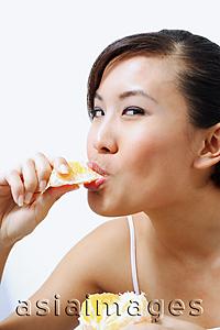 Asia Images Group - Woman eating orange, looking at camera