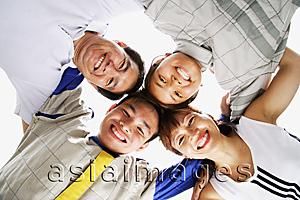 Asia Images Group -  Family of four standing in a circle, arms around each other, looking down at camera