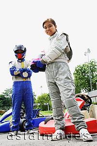 Asia Images Group - Young man and woman wearing motor racing jumpsuits, looking at camera