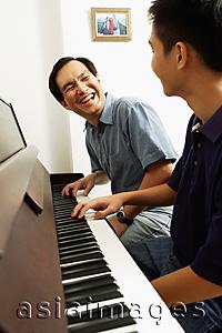 Asia Images Group - Father and son sitting at piano, looking at each other