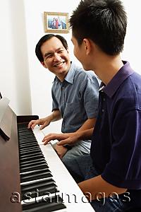 Asia Images Group - Father and son sitting at piano, looking at each other
