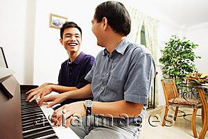 Asia Images Group - Father and son playing piano, sitting side by side