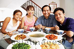 Asia Images Group - Family at home, sitting side by side, looking at camera, food on the table