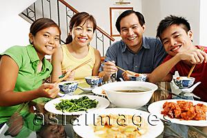 Asia Images Group - Family at home, looking at camera, food on the table in front of them