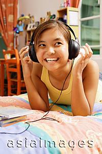 Asia Images Group - Young woman wearing headphones, looking away