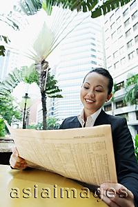 Asia Images Group - Business woman holding newspaper