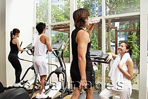 Asia Images Group - Young adults in gym, walking on treadmill, man drinking water