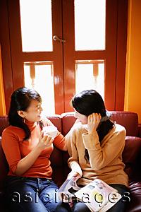 Asia Images Group - Young women sitting on sofa, talking