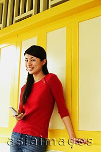 Asia Images Group - Young woman holding mobile phone, smiling at camera